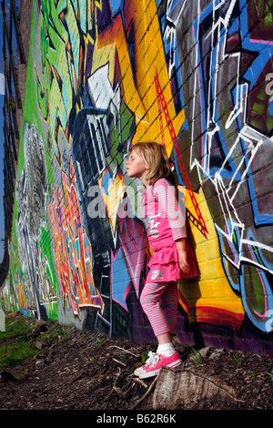 Elle-même fille du soleil en face de l'art du graffiti sur un mur peint à la bombe dans le cadre d'un projet communautaire soleil tan chaleur Banque D'Images