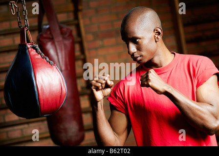 Male boxer pratiquant avec un sac de boxe Banque D'Images