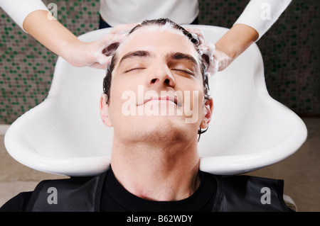 Mid adult man getting hair shampooed at salon Banque D'Images