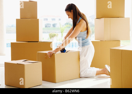 Portrait of a young woman taping cardboard boxes Banque D'Images