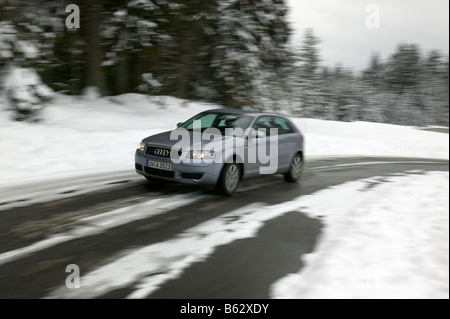 Voiture roulant sur une route couverte de neige en hiver Banque D'Images