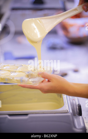 Chocolat blanc fondu est versé dans des moules. Photo par Jim Holden. Banque D'Images