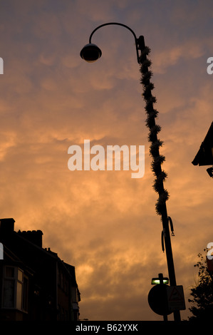 Lumière rougeoyante sur underlit Mammatus nuages à coucher du Soleil, Moody oppressive sentiment étrange, lampadaire en silhouette, UK Banque D'Images