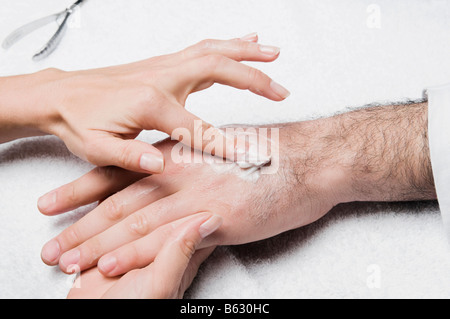 Close-up of a woman's hand l'application de lotion sur la main d'un homme Banque D'Images