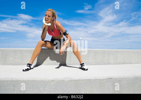Mid adult woman sitting on a ledge Banque D'Images