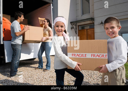 Couple avec leurs enfants à partir de boîtes de déchargement d'un camion pick-up Banque D'Images