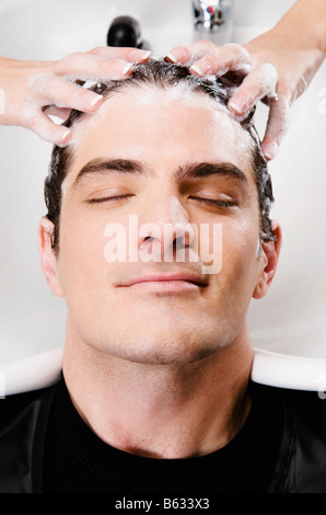 Mid adult man getting hair shampooed at salon Banque D'Images