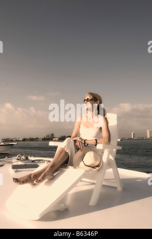 Mid adult woman resting on a deck chair and smiling Banque D'Images