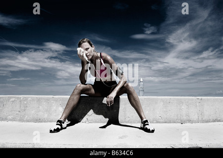 Mid adult woman sitting on a ledge Banque D'Images