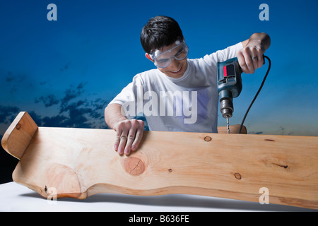 Mid adult man drilling dans une planche en bois Banque D'Images