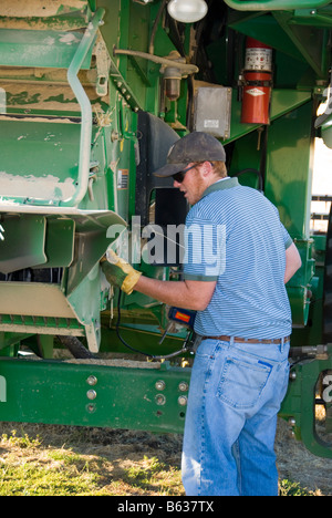 Un conducteur de la moissonneuse-batteuse s'applique de la graisse sur une moissonneuse-batteuse dans le cadre de l'entretien quotidien avant de commencer la récolte dans la région de Palouse Banque D'Images