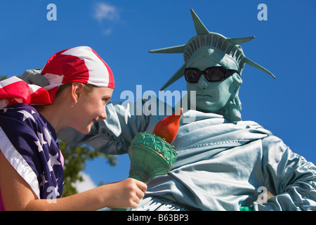 Robes de l'homme comme la Statue de la Liberté avec une jeune fille tenant une torche enflammée à côté de lui, New York City, New York State, USA Banque D'Images