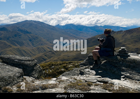 Randonneur avec caméra sur le sommet de Rock Peak, près de Queenstown, South Island, Nouvelle-Zélande Banque D'Images