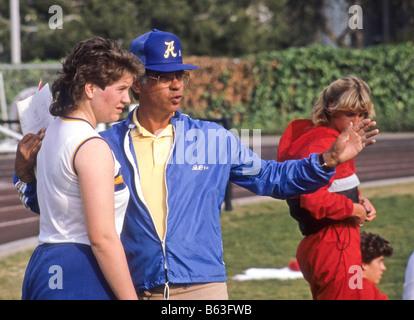 Entraîneur masculin hispaniques encourage coureuse en athlétisme. Banque D'Images