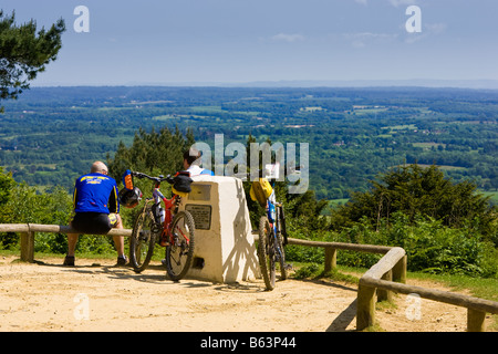 Deux cyclistes à profiter de la vue sur le Weald et South Downs à la campagne haut de Leith Hill, Surrey, Angleterre, Royaume-Uni Banque D'Images