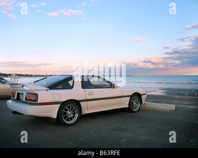 Une voiture de sport blanc stationné à la plage Banque D'Images