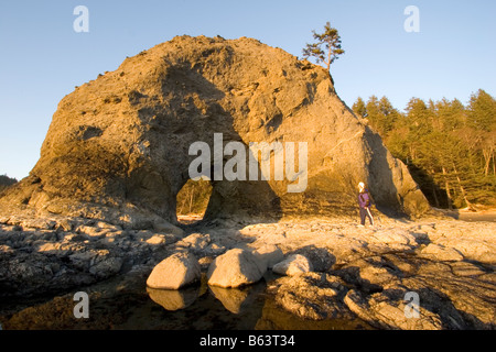 Un randonneur jouit de trou dans le mur le long de la plage de Rialto côte Olympique Olympic National Park Washington Banque D'Images