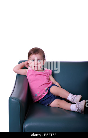 Une petite fille sur un fauteuil en cuir vert en face d'un fond blanc Banque D'Images