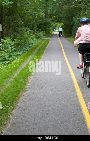 Piste cyclable d'Ottawa : deux femmes casqué dans un cycle très droit et pavée bordée de jaune Ottawa piste cyclable autrefois une ligne de chemin de fer Banque D'Images