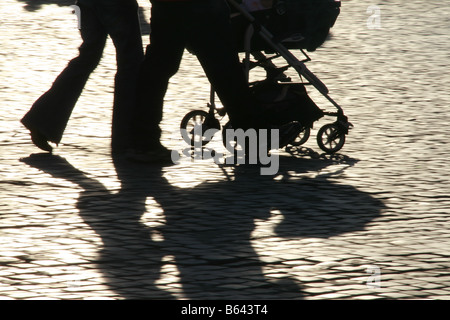 Les gens de l'ombre de vitesse rapide pieds jambes poussant dans la pram bébé soleil en rue en ville Banque D'Images