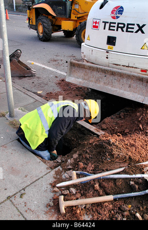 Un ouvrier dans le processus d'élimination d'un trou sous la chaussée, afin de préparer de nouveaux tuyaux. Banque D'Images