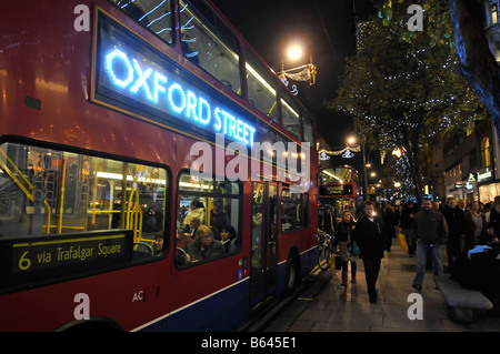 Oxford street et décorations de Noël avec bus publicitaires lumineux de bord et shoppers Banque D'Images