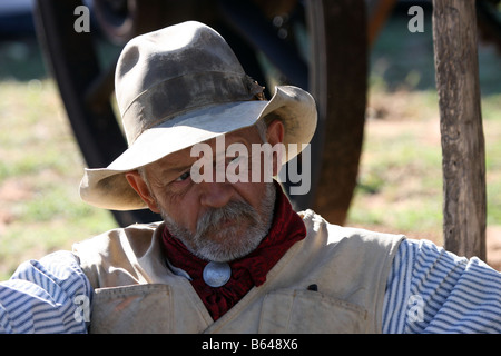 Un vieux cowboy minuterie appuyé contre son sac à côté de la selle et chuck wagon Banque D'Images