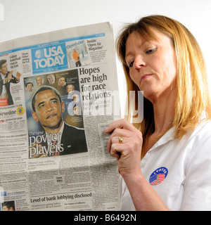 J'ai voté Woman Reading newspaper badge montrant Barack Obama annonçant son élection gagner en novembre 2008 Banque D'Images