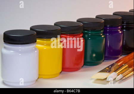 Les peintures et les pinceaux de l'artiste assise sur une table avec un fond blanc. Banque D'Images