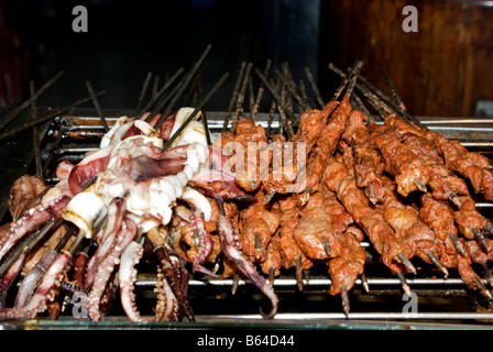 Les calmars et les brochettes de porc grillées sur un barbecue en acier inoxydable grill dans de minuscules food dans le Temple du dieu de la ville shopping area Banque D'Images