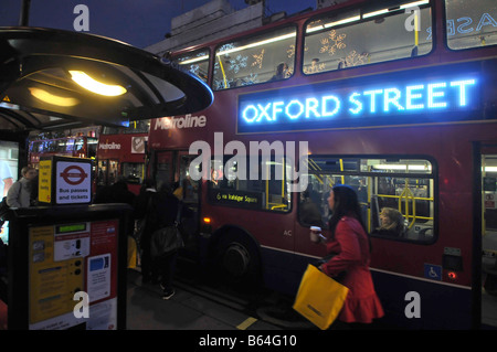 Arrêt de bus d'Oxford street et de bus avec panneau publicitaires lumineux et shopper Banque D'Images