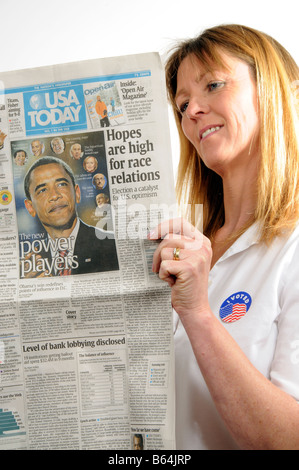 J'ai voté Woman Reading newspaper badge montrant Barack Obama annonçant son élection gagner en novembre 2008 Banque D'Images