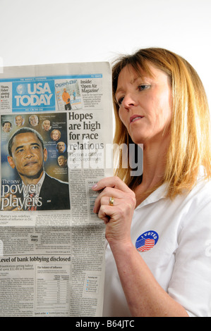 J'ai voté Woman Reading newspaper badge montrant Barack Obama annonçant son élection gagner en novembre 2008 Banque D'Images