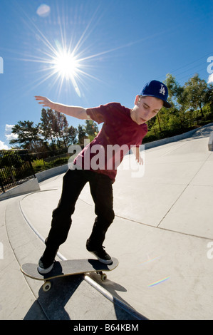 Jeune homme faisant un grind sur un skate park Banque D'Images