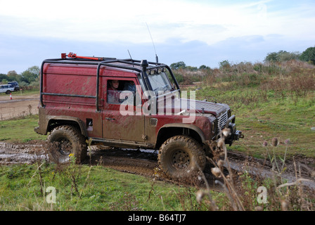 Éclaboussé de boue Land Rover Defender 90 équipé pour travailler hors route avec suspension cage rouleau soulevé contre les pneus à la qualité du treuil Banque D'Images