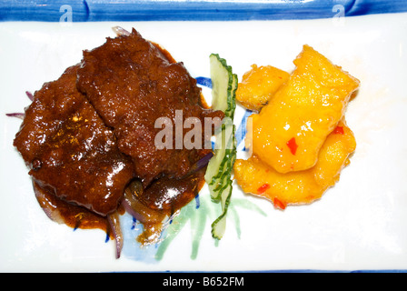 Filet sauté de boeuf et l'oignon dans la sauce aigre-douce aux épices poissons battues avec tranche de concombre anglais garnir Banque D'Images