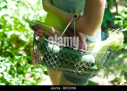 Teenage girl transportant corbeille en fil de légumes Banque D'Images