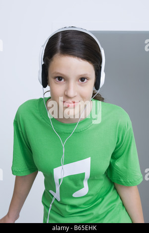 Preteen girl wearing tee-shirt imprimé avec des notes de musique, l'écoute au casque, smiling Banque D'Images