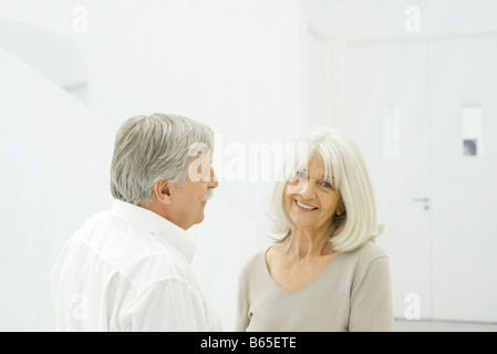 Couple debout face à face, woman smiling at camera Banque D'Images