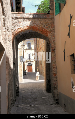 Une femme porte ses courses à travers les rues étroites de Sanseplocro en Toscane, Italie. Banque D'Images