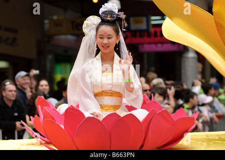 Jeune fille en costume traditionnel chinois assis sur une fleur de lotus au cours d'un défilé du Nouvel An chinois. Banque D'Images
