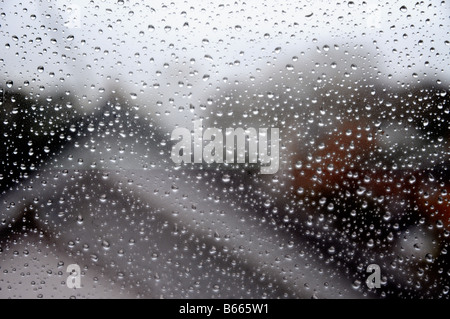Vue d'un toit par une pluie éclaboussés fenêtre. Banque D'Images
