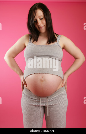 Une vue sur la tête d'un dark haired 38 semaines (9 mois) enceinte femme debout portant des vêtements gris occasionnels. Banque D'Images