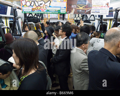 Les voyageurs debout dans wagon de chemin de fer sur la ligne Chuo Shinjuku Tokyo Japon Banque D'Images