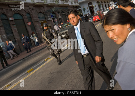 Equateur Quito policier avec méfiance l'homme regarde le costume d'affaires en marche dernières spectateurs remplissant rue bondée au Teatro Sucre Banque D'Images