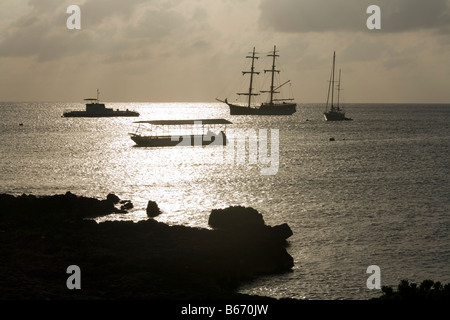 Îles Caïmans l'île Grand Cayman George Town soleil couchant silhouettes bateaux ancrés le long du littoral des Caraïbes Banque D'Images