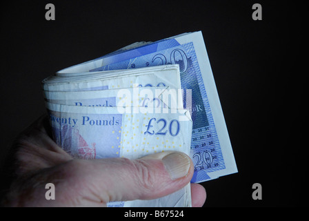 Poignée d'anglais £20 billets détenus dans un rouleau Banque D'Images