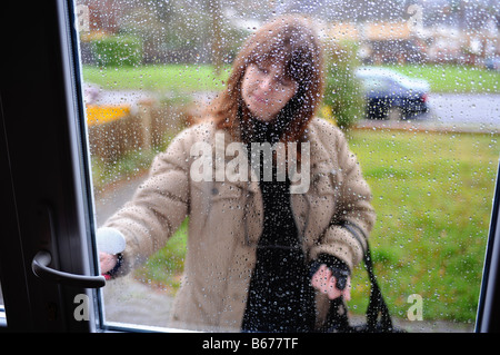 Jour de pluie en Angleterre, Grande-Bretagne avec des femmes d'ouvrir sa porte d'entrée Banque D'Images