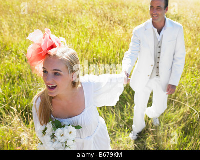 Couple marié de marcher dans un champ Banque D'Images