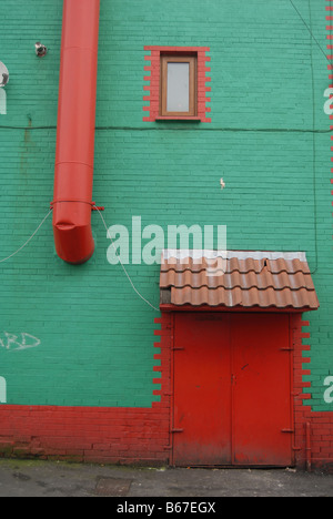 Une porte arrière peint en rouge situé dans un mur de couleur vert profond forme une composition , East Belfast , Irlande du Nord Banque D'Images